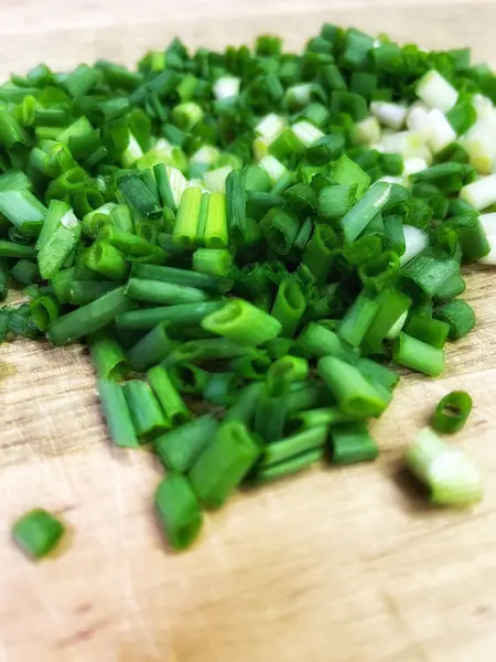 Doğranmış yeşil soğanlar, masanın üzerindeki tahta kesme tahtasının üzerinde. Mutfakta, yemek, yemek, yemek.