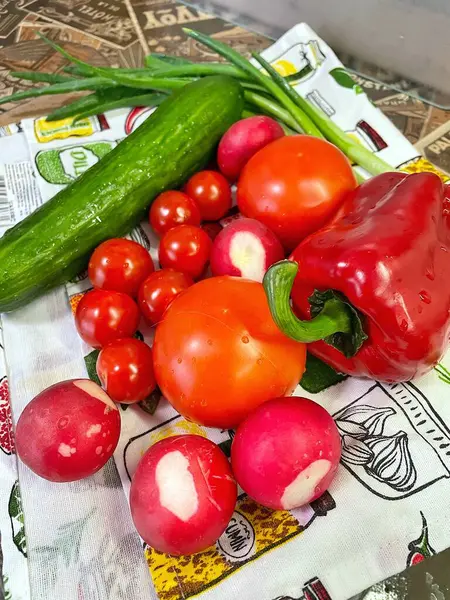 Mutfaktaki masada organik kırmızı ve yeşil sebzeler, domates, soğan, kırmızımsı, salatalık, biber. 