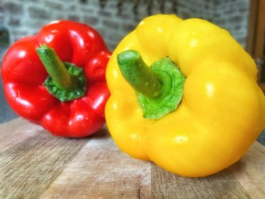 Tahta bir masada taze renkli dolmalık biber, kırmızı biber.