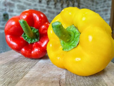 Tahta bir masada taze renkli dolmalık biber, kırmızı biber.