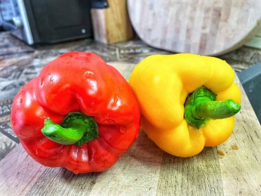 Tahta bir masada taze renkli dolmalık biber, kırmızı biber.