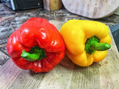 Tahta bir masada taze renkli dolmalık biber, kırmızı biber.