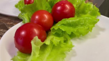 Yemek, vitaminler, yeşil marul yaprakları ve kırmızı domatesler bir tabakta yatıyor.