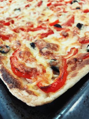 Domatesli pizza ve siyah tabakta peynir.