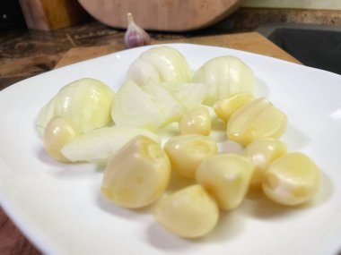 Beyaz tabakta sarımsak ve soğan, yemek. 