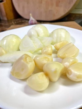 Beyaz tabakta sarımsak ve soğan, yemek. 