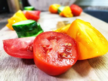 taze organik sebzeler, kırmızı ve sarı domatesler, yeşil salatalık, vegan, ahşap tahtada. 