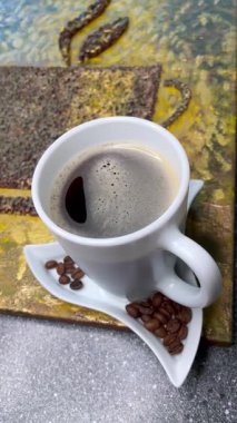 Eşsiz yaratıcı yaklaşım, kahve çekirdekleri ve bir fincan aromatik kahve, zarif ve pahalı.