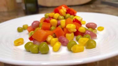 Beyaz tabakta parlak renkli sebzeler: mısır, bezelye, fasulye, biber, havuç, sağlığa iyi gelir, yemek pişirme