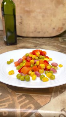 Beyaz tabakta parlak renkli sebzeler: mısır, bezelye, fasulye, biber, havuç, sağlığa iyi gelir, yemek pişirme