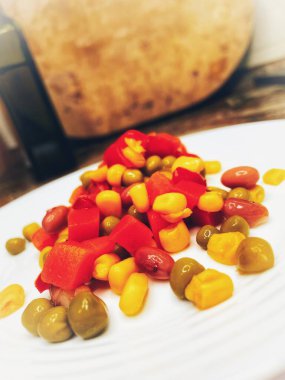 Beyaz tabakta parlak renkli sebzeler: mısır, bezelye, fasulye, biber, havuç, sağlığa iyi gelir, yemek pişirme