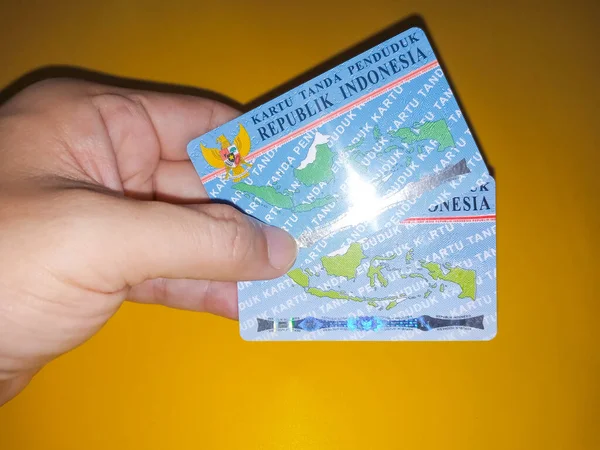 男の手は黄色の背景を持つ2つのインドネシアの市民Idカードを保持 インドネシアの身分証明書の写真イラスト Ktpだ 記事やアイデンティティ関連の問題に最適です — ストック写真