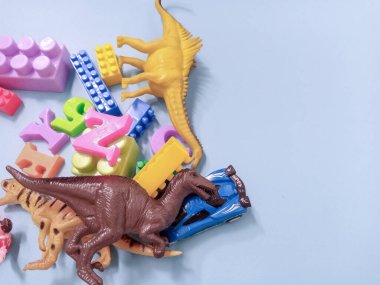 Çocuk oyuncakları geçmişi. Renkli bloklar, alfabe oyuncakları ve dinazorlar gökyüzündeki mavi arka plan çerçevesi.