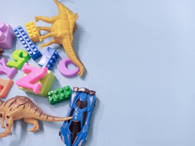 Çocuk oyuncakları geçmişi. Renkli bloklar, alfabe oyuncakları ve dinazorlar gökyüzündeki mavi arka plan çerçevesi.