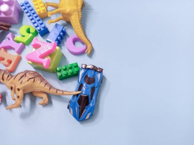 Çocuk oyuncakları geçmişi. Renkli bloklar, alfabe oyuncakları ve dinazorlar gökyüzündeki mavi arka plan çerçevesi.