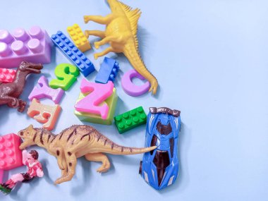 Çocuk oyuncakları geçmişi. Renkli bloklar, alfabe oyuncakları ve dinazorlar gökyüzündeki mavi arka plan çerçevesi.