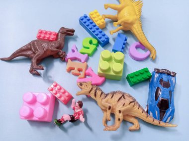 Çocuk oyuncakları geçmişi. Renkli bloklar, alfabe oyuncakları ve dinazorlar gökyüzündeki mavi arka plan çerçevesi.