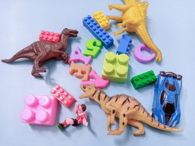 Çocuk oyuncakları geçmişi. Renkli bloklar, alfabe oyuncakları ve dinazorlar gökyüzündeki mavi arka plan çerçevesi.