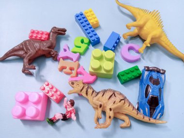 Çocuk oyuncakları geçmişi. Renkli bloklar, alfabe oyuncakları ve dinazorlar gökyüzündeki mavi arka plan çerçevesi.