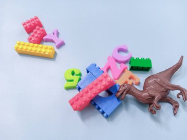 Çocuk oyuncakları geçmişi. Renkli bloklar, alfabe oyuncakları ve dinazorlar gökyüzündeki mavi arka plan çerçevesi.