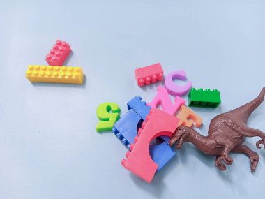 Çocuk oyuncakları geçmişi. Renkli bloklar, alfabe oyuncakları ve dinazorlar gökyüzündeki mavi arka plan çerçevesi.