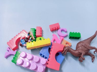 Çocuk oyuncakları geçmişi. Renkli bloklar, alfabe oyuncakları ve dinazorlar gökyüzündeki mavi arka plan çerçevesi.