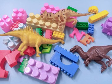 Çocuk oyuncakları geçmişi. Renkli bloklar, alfabe oyuncakları ve dinazorlar gökyüzündeki mavi arka plan çerçevesi.