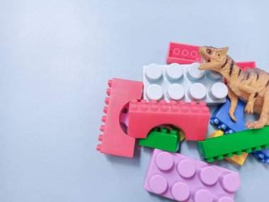 Çocuk oyuncakları geçmişi. Renkli bloklar, alfabe oyuncakları ve dinazorlar gökyüzündeki mavi arka plan çerçevesi.