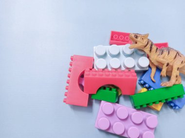 Çocuk oyuncakları geçmişi. Renkli bloklar, alfabe oyuncakları ve dinazorlar gökyüzündeki mavi arka plan çerçevesi.