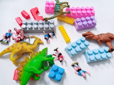 Dinozor oyuncağı figürlü çocuk renkli plastik blok tuğlaları. Beyaz arka planda renkli çocuk oyuncakları