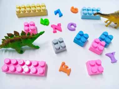 Çocuk oyuncakları geçmişi. Renkli bloklar, alfabe oyuncakları ve Dinazorların oyuncakları beyaz arkaplandaki çerçeveler.