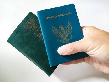 Endonezya Pasaportu. Endonezya 'nın iki resmi yeşil pasaport sahibi insan eliyle beyaz arka planda..