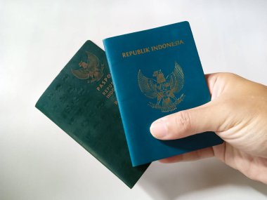 Endonezya Pasaportu. Endonezya 'nın iki resmi yeşil pasaport sahibi insan eliyle beyaz arka planda..