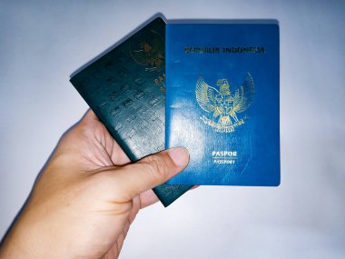 Endonezya Pasaportu. Endonezya 'nın iki resmi yeşil pasaport sahibi insan eliyle beyaz arka planda..