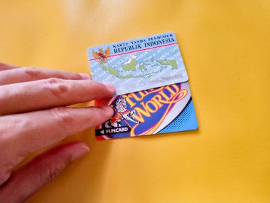 İki Endonezya vatandaşı kimliği ve sarı arka planlı bir zaman kartı. Endonezya kimlik kartı illüstrasyonu. KTP. Makaleler ya da kimlik sorunları için mükemmel.