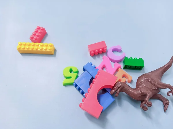 Çocuk oyuncakları geçmişi. Renkli bloklar, alfabe oyuncakları ve dinazorlar gökyüzündeki mavi arka plan çerçevesi.