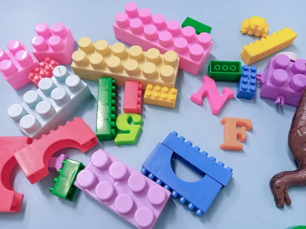 Kid Toys background. Colorful blocks, alphabet toys and Dinosaurs toys frame on sky blue background.