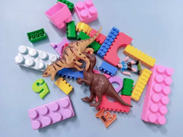 Kid Toys background. Colorful blocks, alphabet toys and Dinosaurs toys frame on sky blue background.
