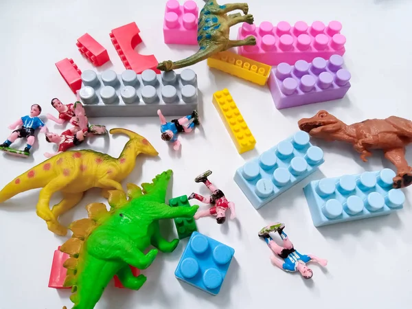 Dinozor oyuncağı figürlü çocuk renkli plastik blok tuğlaları. Beyaz arka planda renkli çocuk oyuncakları