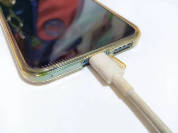 İzole edilmiş beyaz arka planda enerji bankasıyla şarj olan akıllı telefon. Telefon şarj cihazına bağlandı