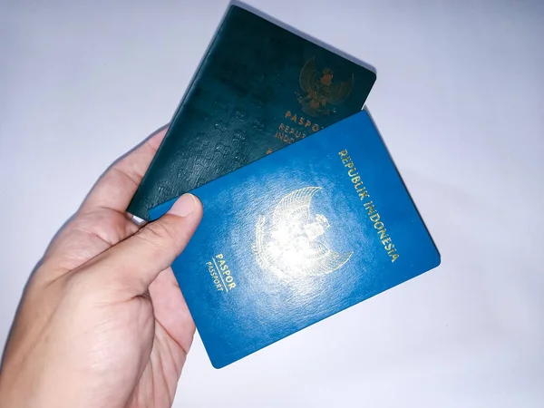 インドネシアのパスポートを保持する手 インドネシア共和国の2人の役人白い背景に人間の手に緑のパスポートカード — ストック写真