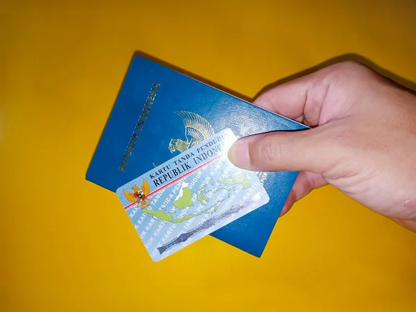 Άνδρας Χέρι Κρατώντας Ινδονησιακή Ταυτότητα Πολίτη Και Διαβατήριο Κίτρινο Φόντο — Φωτογραφία Αρχείου