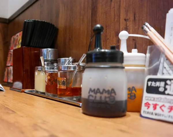 庞迪亚纳克2015年11月20日 在日本餐馆的木制柜台上 餐馆用罐子或瓶子调料 日本红辣椒片和酱油瓶 点菜菜单和铅笔 — 图库照片