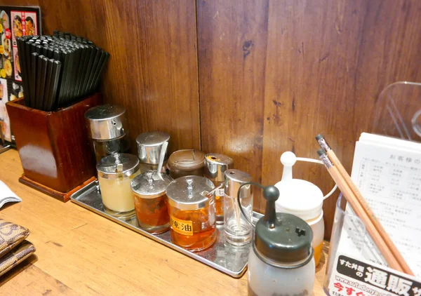 庞迪亚纳克2015年11月20日 在日本餐馆的木制柜台上 餐馆用罐子或瓶子调料 日本红辣椒片和酱油瓶 点菜菜单和铅笔 — 图库照片