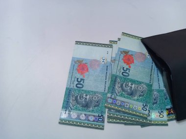 Beyaz arka planda izole edilmiş Malezya Ringgit banknotları olan siyah deri cüzdan. Siyah cüzdandan 50 ringgit Malezya banknotu