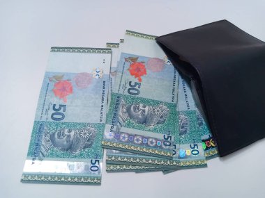 Beyaz arka planda izole edilmiş Malezya Ringgit banknotları olan siyah deri cüzdan. Siyah cüzdandan 50 ringgit Malezya banknotu