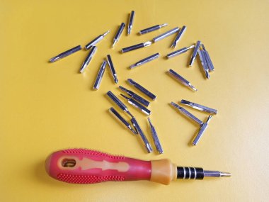 Çeşitli hortumları olan tornavida. Değişebilir tornavida seti farklı metal başlıklar ve bitler sarı arkaplan.