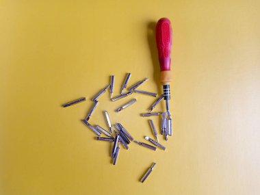 Çeşitli hortumları olan tornavida. Değişebilir tornavida seti farklı metal başlıklar ve bitler sarı arkaplan.