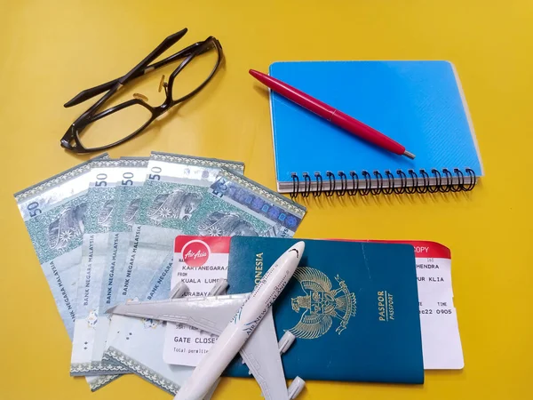 Pontianak 2022年12月27日 旅行コンセプト コピースペース付き黄色の背景にペン マレーシアリンギットのお金 パスポート 飛行機 チケット 三脚を旅行するための準備 — ストック写真