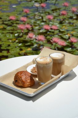Kahve fincanı ahşap tepside ve masada kruvasan.